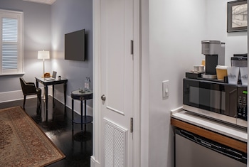 A bathroom with a white sink, black countertop, and a large mirror. There are two bottles on the countertop and a towel hanging on the wall. at The Pelham Hotel