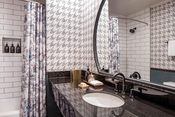 A bathroom with a shelf holding three bottles of