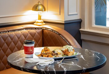 A cozy seating area with a green sofa, a round coffee table, and a bar area with a marble countertop. at The Pelham Hotel