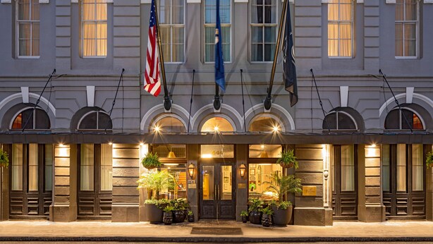 A hotel facade with a classic architectural style, featuring arched windows and a central entrance.