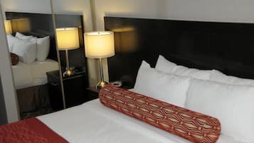 Una habitación de hotel con una cama bien hecha, dos lámparas de noche, una mesita de noche y un espejo.