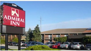A hotel sign with the name 'Admiral Inn' and a parking lot with several cars.