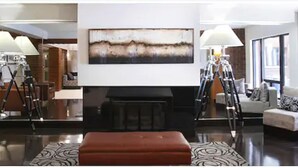 A modern living room with a fireplace, a large abstract painting, and a sofa.