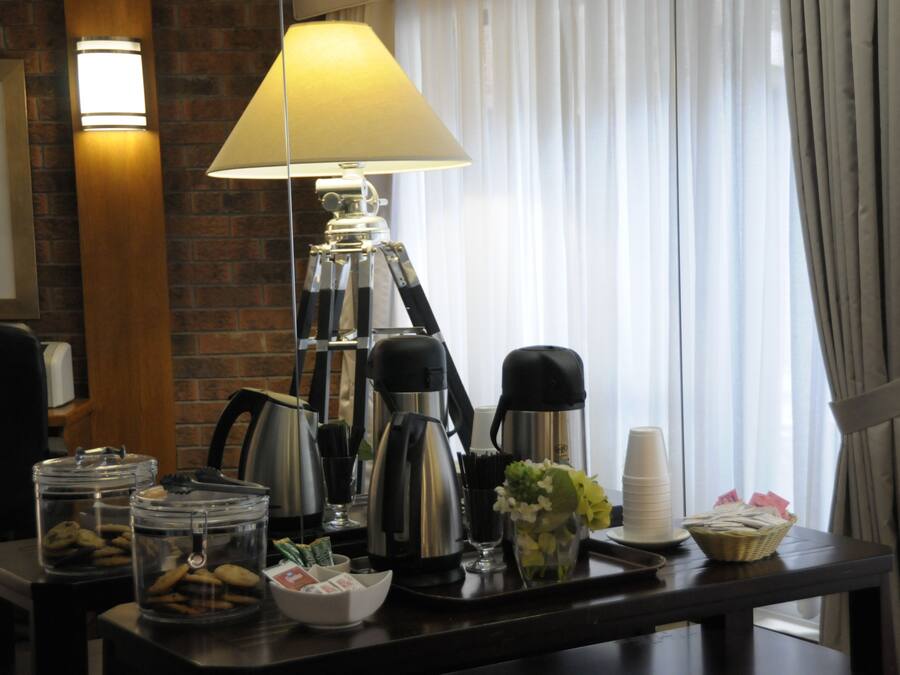 A breakfast bar with coffee makers, a lamp, and various breakfast items.