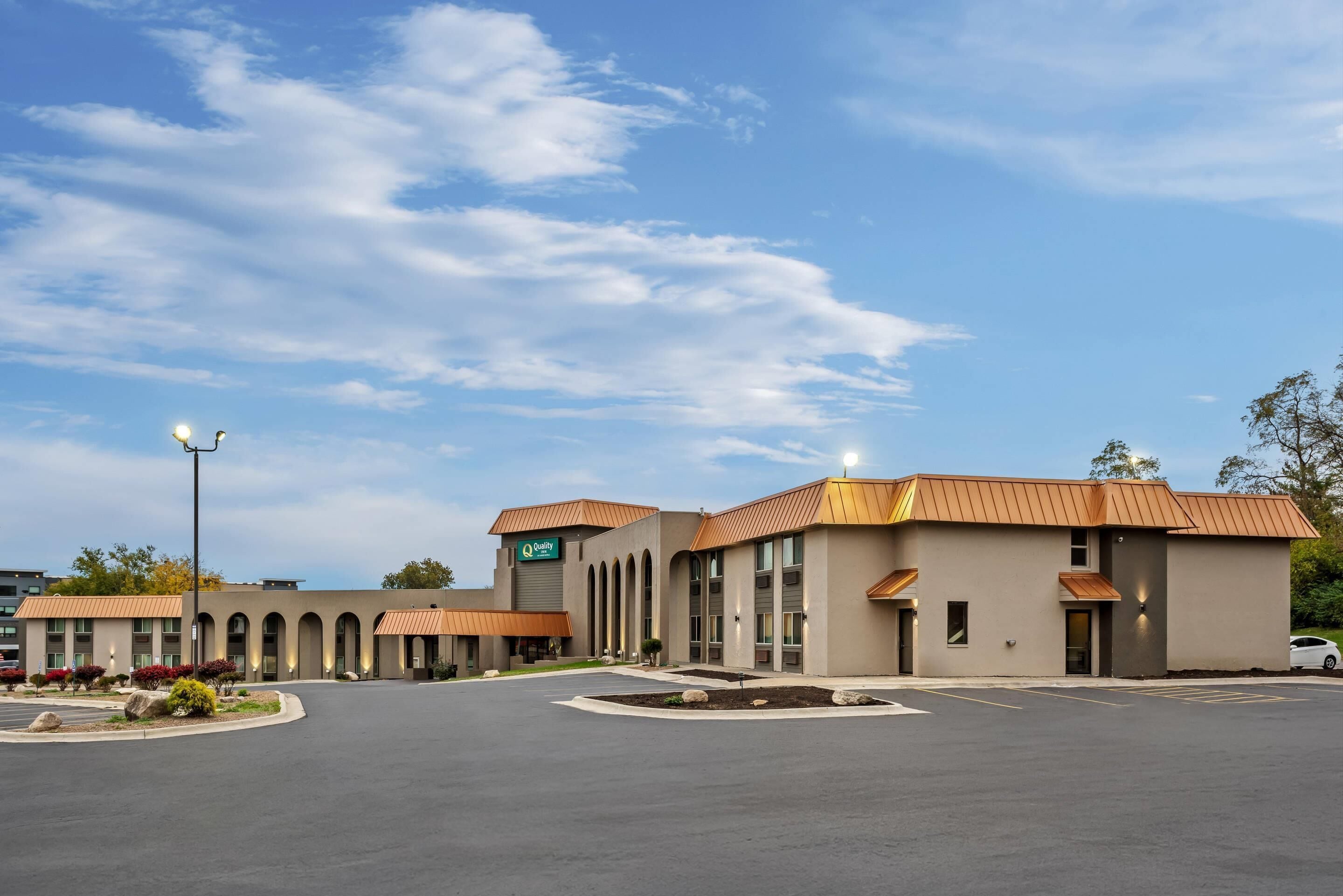 A hotel with a central building and a parking lot.