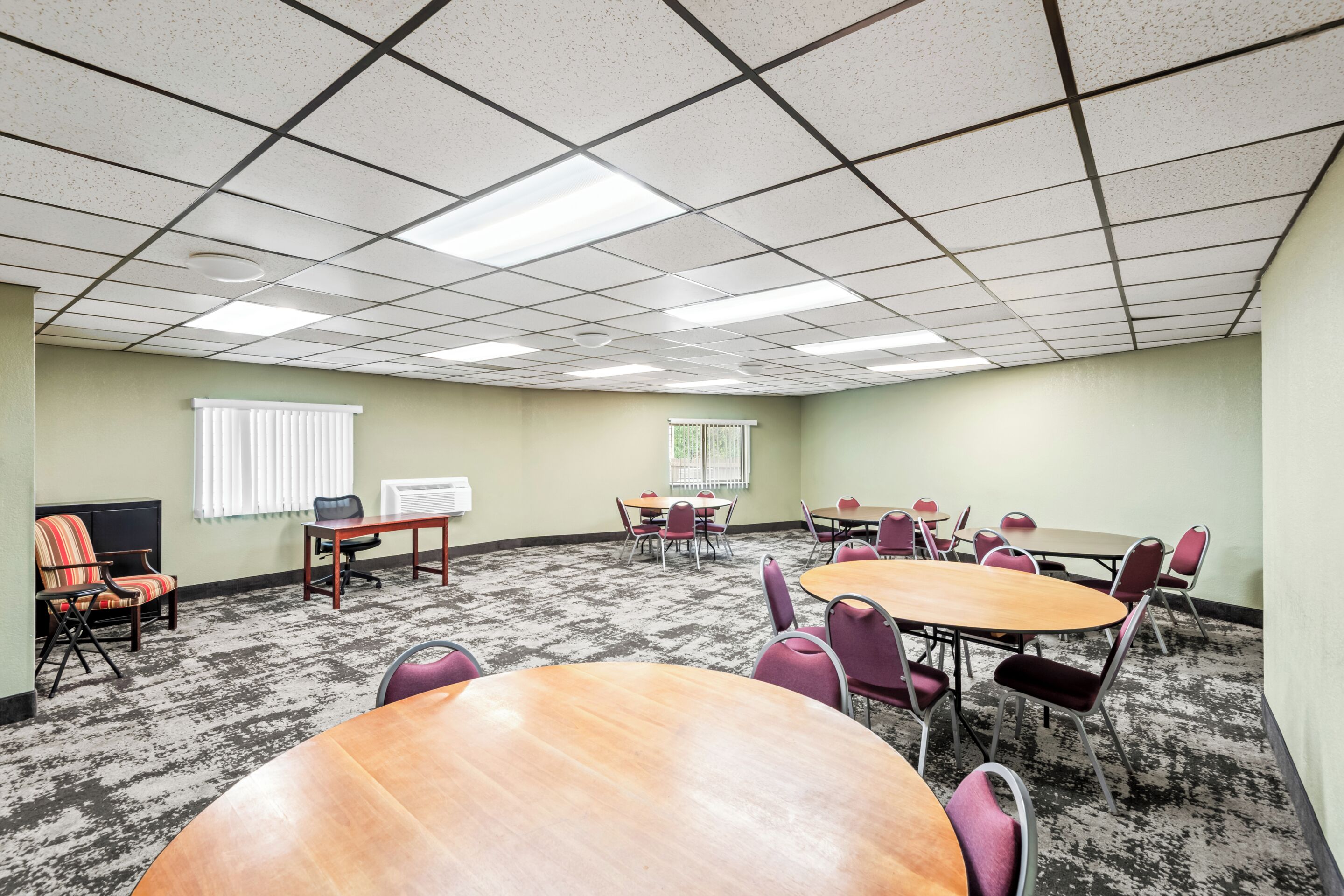 A conference room with a large oval table, several smaller round tables, and chairs.