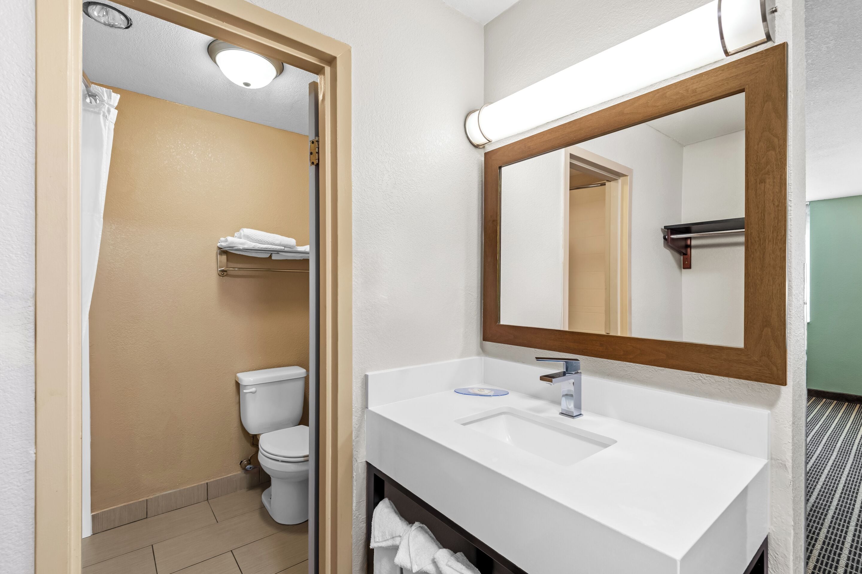 A bathroom with a white sink, mirror, and toilet.