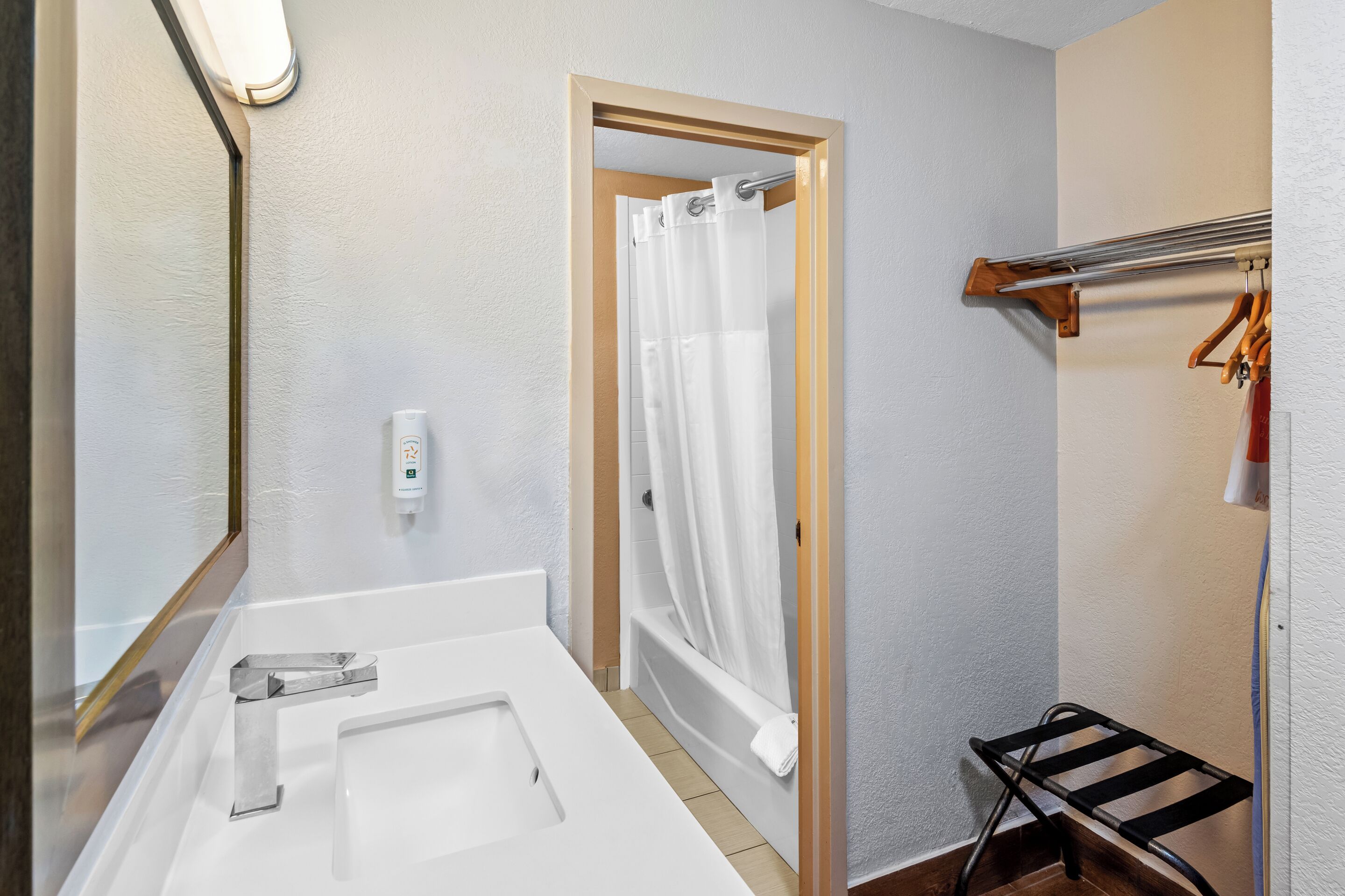 A bathroom with a bathtub, a shower curtain, a towel rack, and a towel rack.