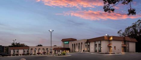 A hotel with a modern design, featuring a central building with a flat roof and multiple windows.