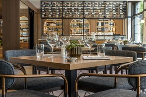 A restaurant interior with a long table set for dining, surrounded by upholstered chairs. - DoubleTree by Hilton Berlin Ku'damm (Berlin)