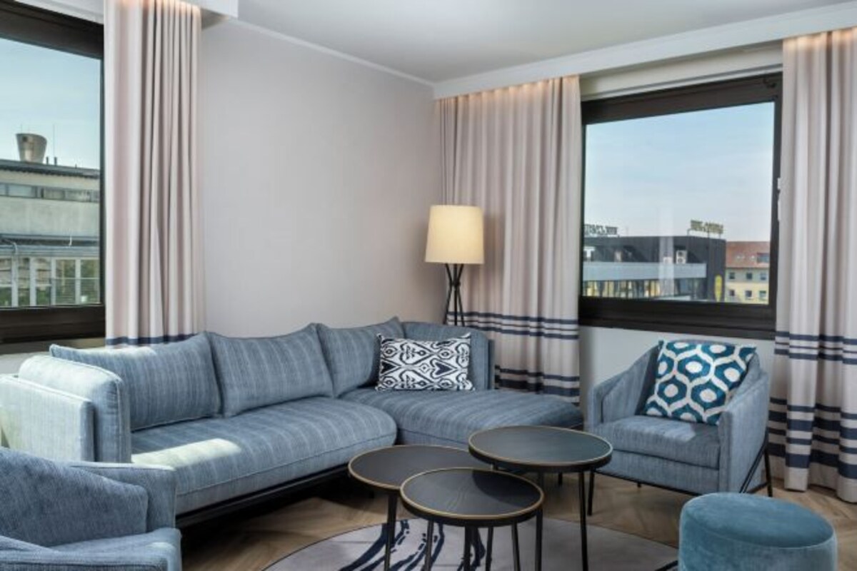 A modern living room with a sectional sofa, two round side tables, and a patterned armchair.