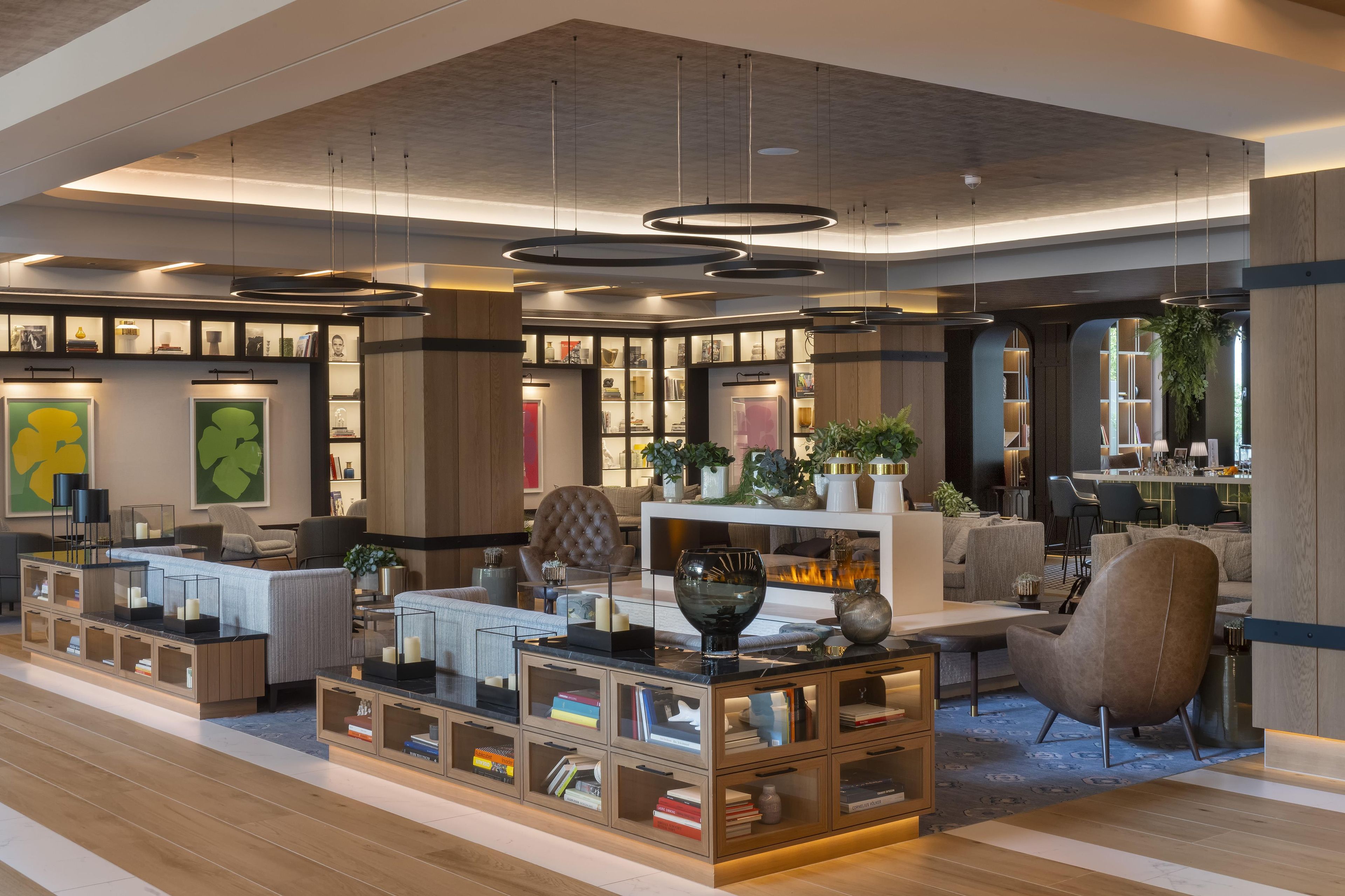 Um interior moderno com área de estar central, estantes e lareira.
