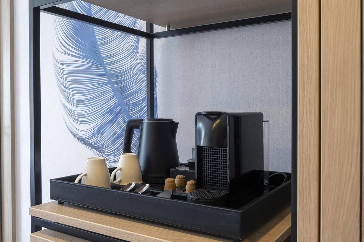 Una kitchenette compacta con cafetera, hervidor y tetera sobre una encimera de madera.