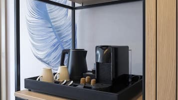 Uma cozinha compacta com cafeteira, chaleira e bule sobre bancada de madeira.