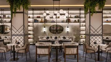 Um interior moderno com uma área de estar central, rodeada por estantes de livros e iluminação decorativa.