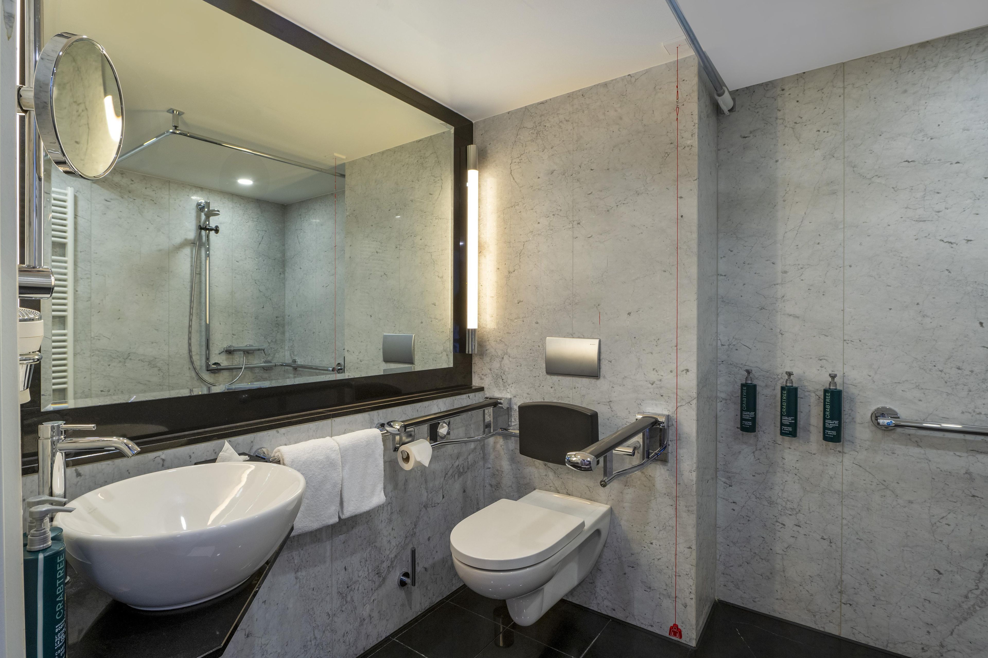 A modern bathroom with two sinks, a toilet, a shower, and a large mirror.