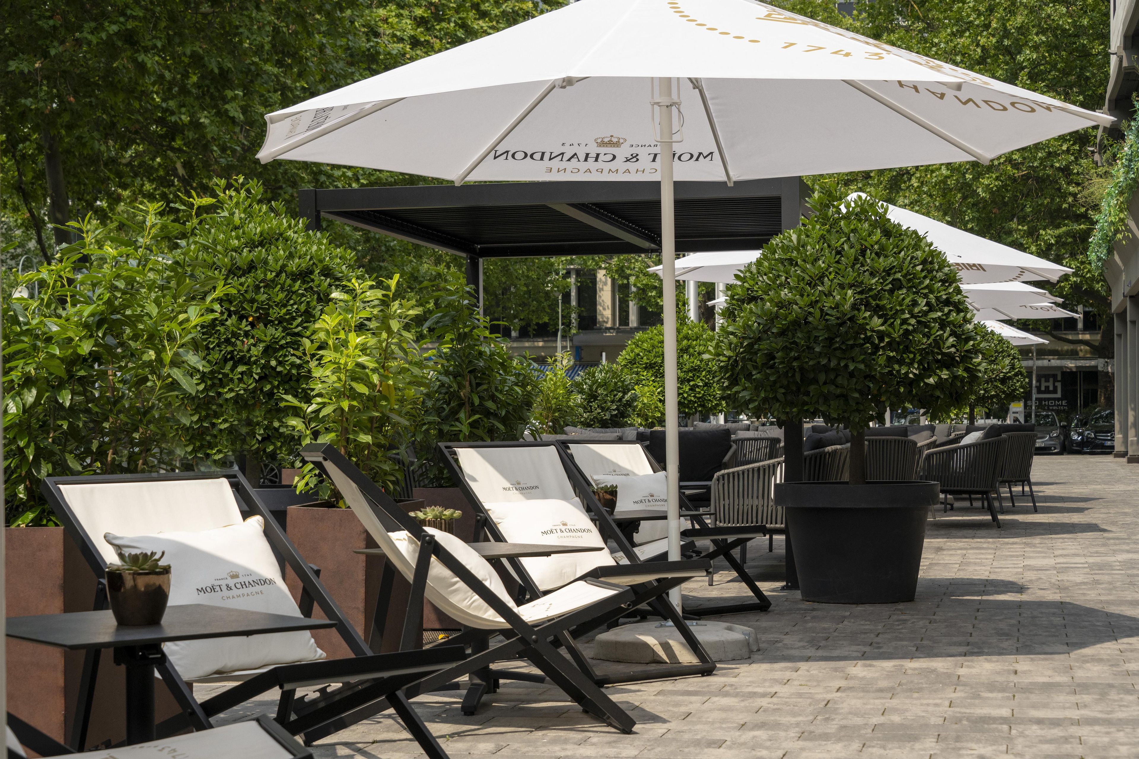 Outdoor seating with umbrellas, lounge chairs, and potted plants.