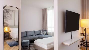 Una habitación de hotel con una cama, un sofá, un televisor y un espejo.