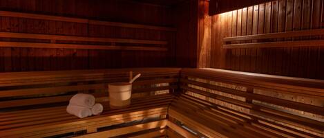 A wooden sauna with benches and a wooden bucket.