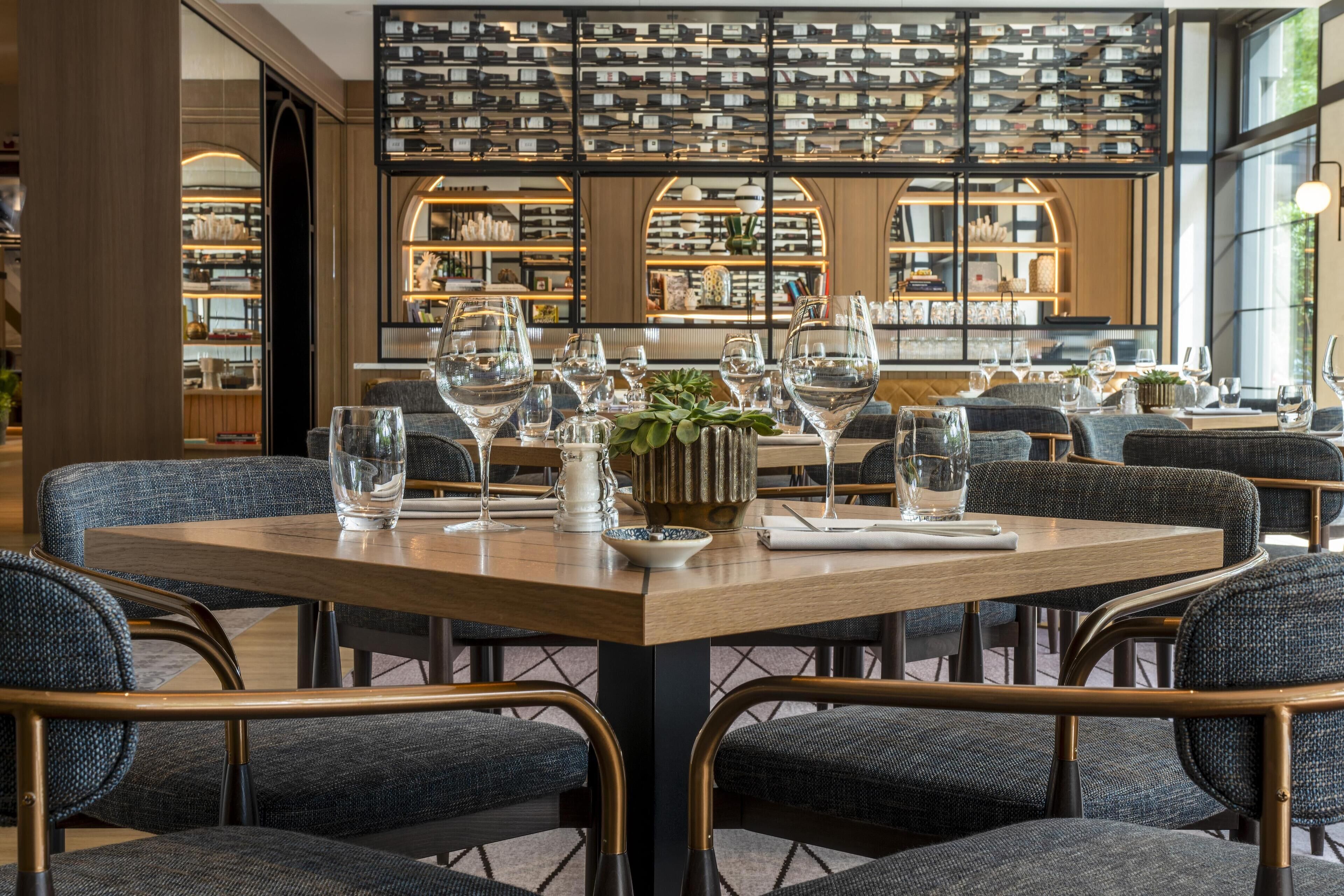 Un restaurant avec une table en bois dressée pour le repas, entourée de chaises rembourrées.