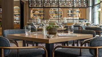 Un restaurant avec une table en bois dressée pour le repas, entourée de chaises rembourrées.