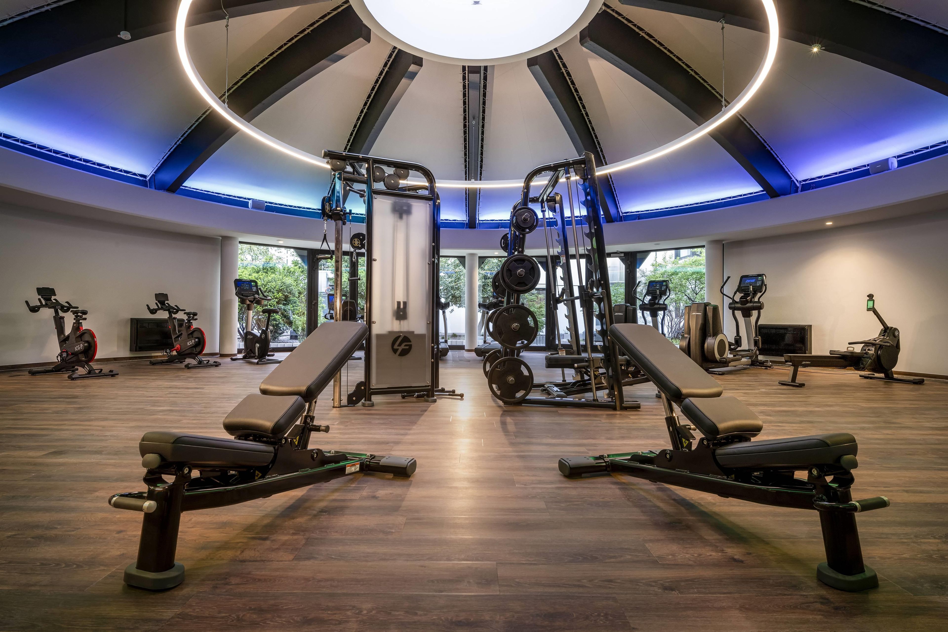Ein Fitnessstudio mit Laufbändern, Gewichten und Bänken.