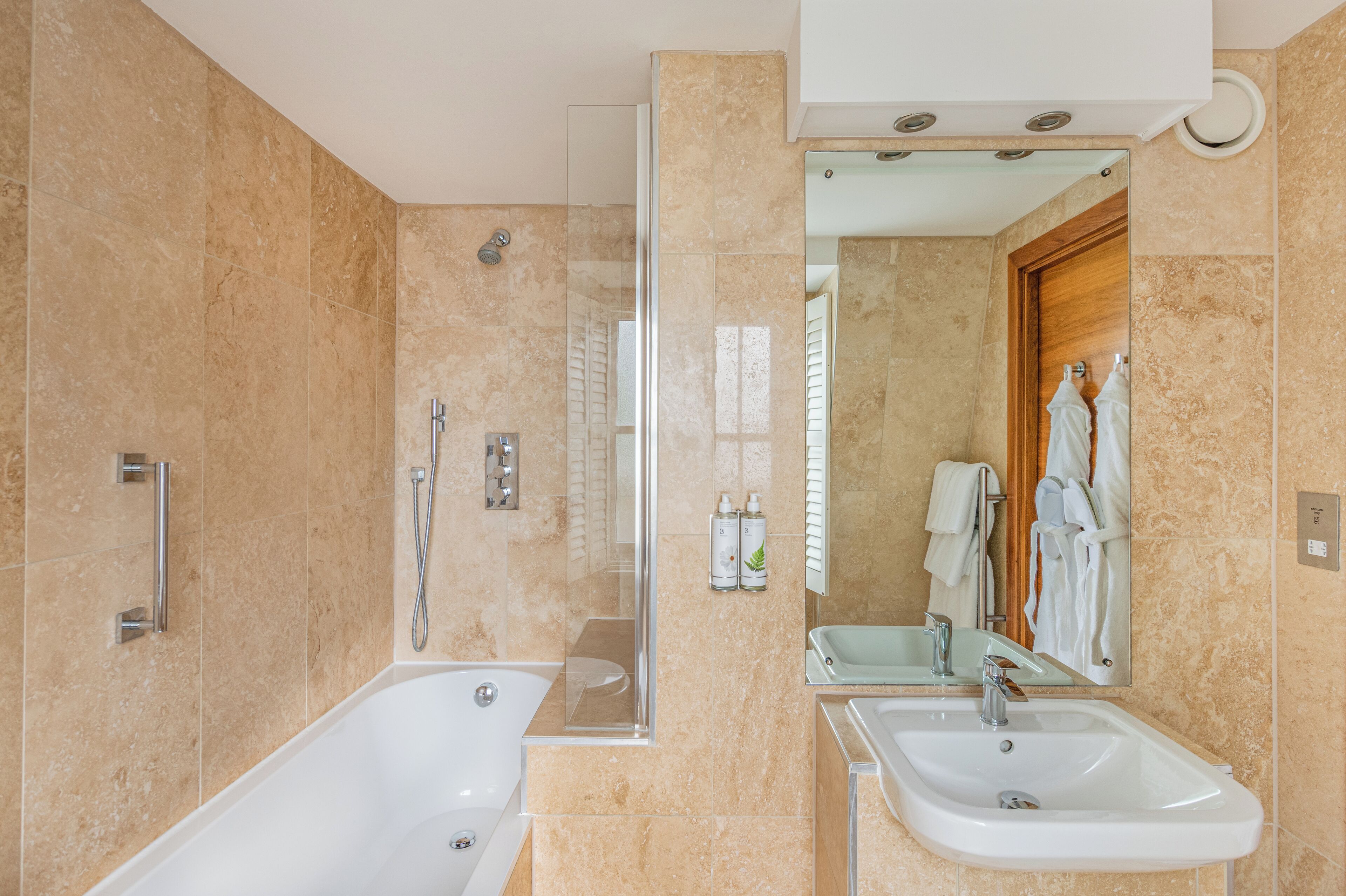 A modern bathroom with a bathtub, shower, and sink.