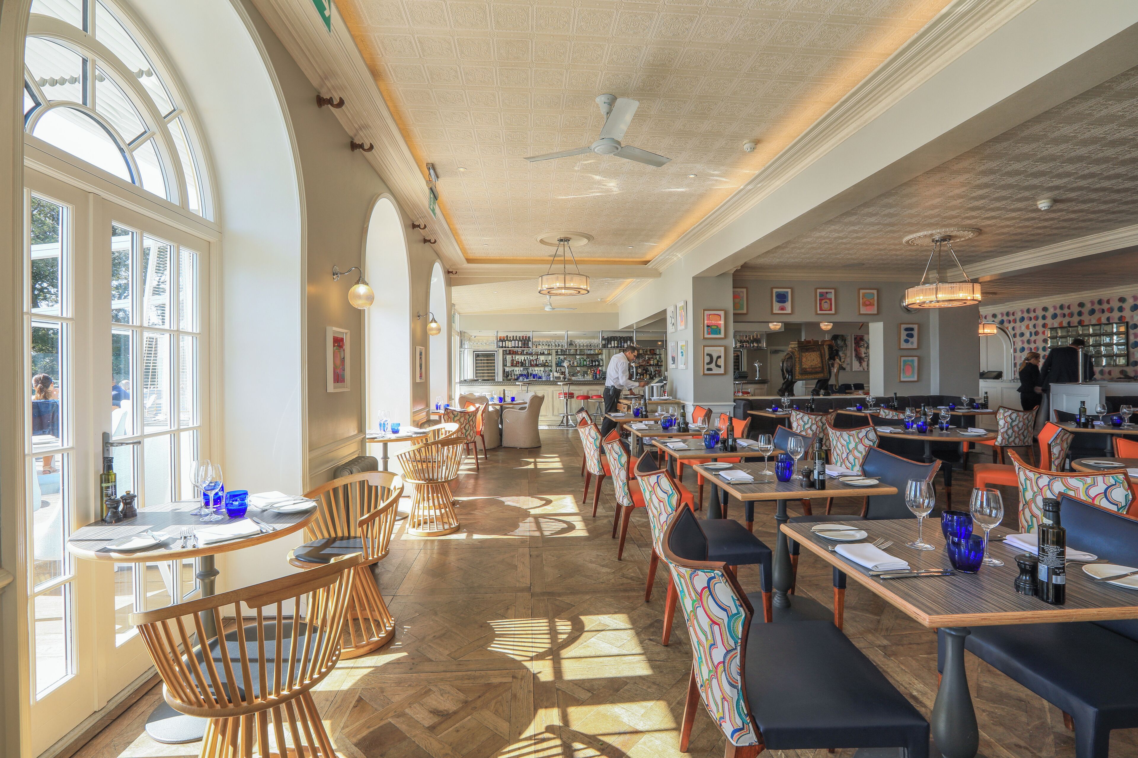 Un restaurante espacioso con techos altos, amplias ventanas y diversas opciones de asientos.
