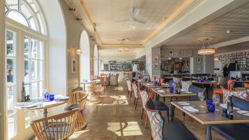 Un restaurante espacioso con techos altos, amplias ventanas y diversas opciones de asientos.