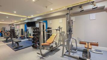 A gym with various exercise equipment, including a bench press, dumbbells, and weight machines.