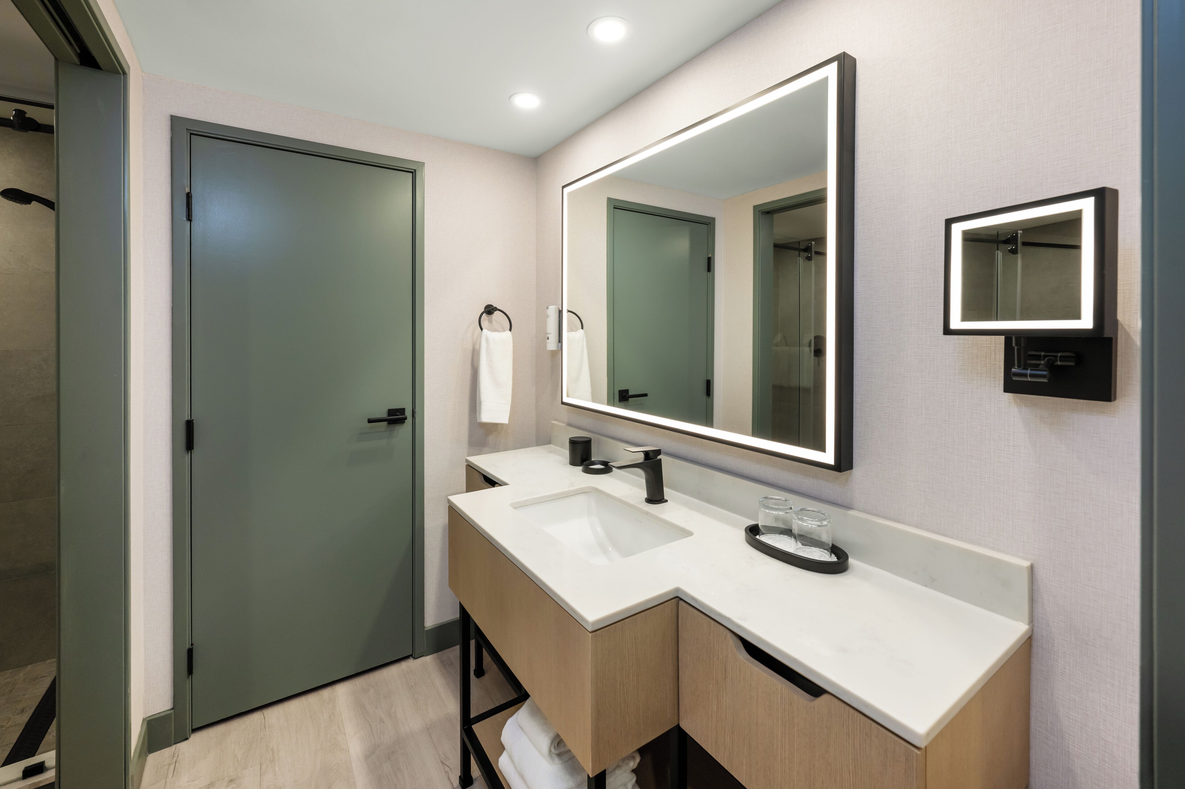 A modern bathroom with a double sink, a large mirror, and a towel rack.