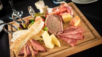 Una tabla de fiambres con varios tipos de carne, quesos y aceitunas sobre una tabla de madera.
