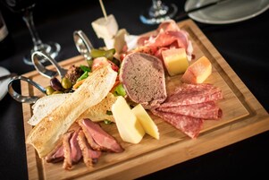 Una tabla de fiambres con varios tipos de carne, quesos y aceitunas sobre una tabla de madera.