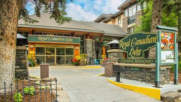 The exterior of the Royal Canadian Lodge, featuring a stone facade, large windows, and a welcoming entrance with a signboard.
