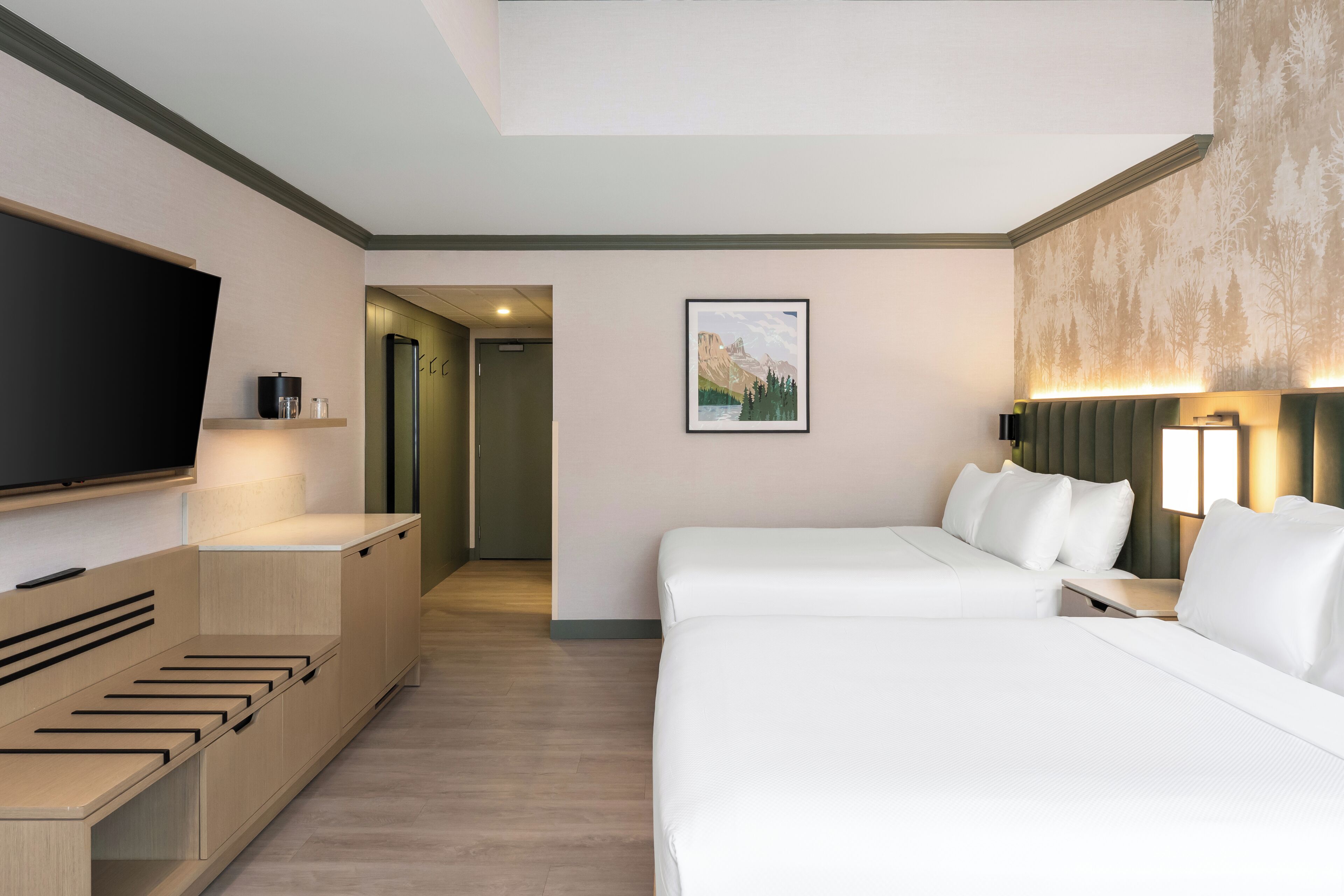 A hotel room with a bed, a TV, a desk, and a painting on the wall.