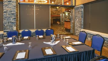 Un salón de conferencias con una larga mesa, sillas azules y una chimenea al fondo.