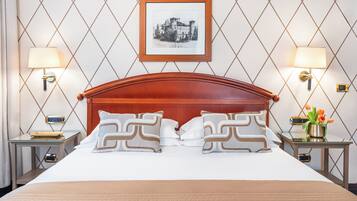 Una habitación de hotel con una cama grande, dos mesitas de noche, un cuadro enmarcado en la pared y una mesita con una lámpara.