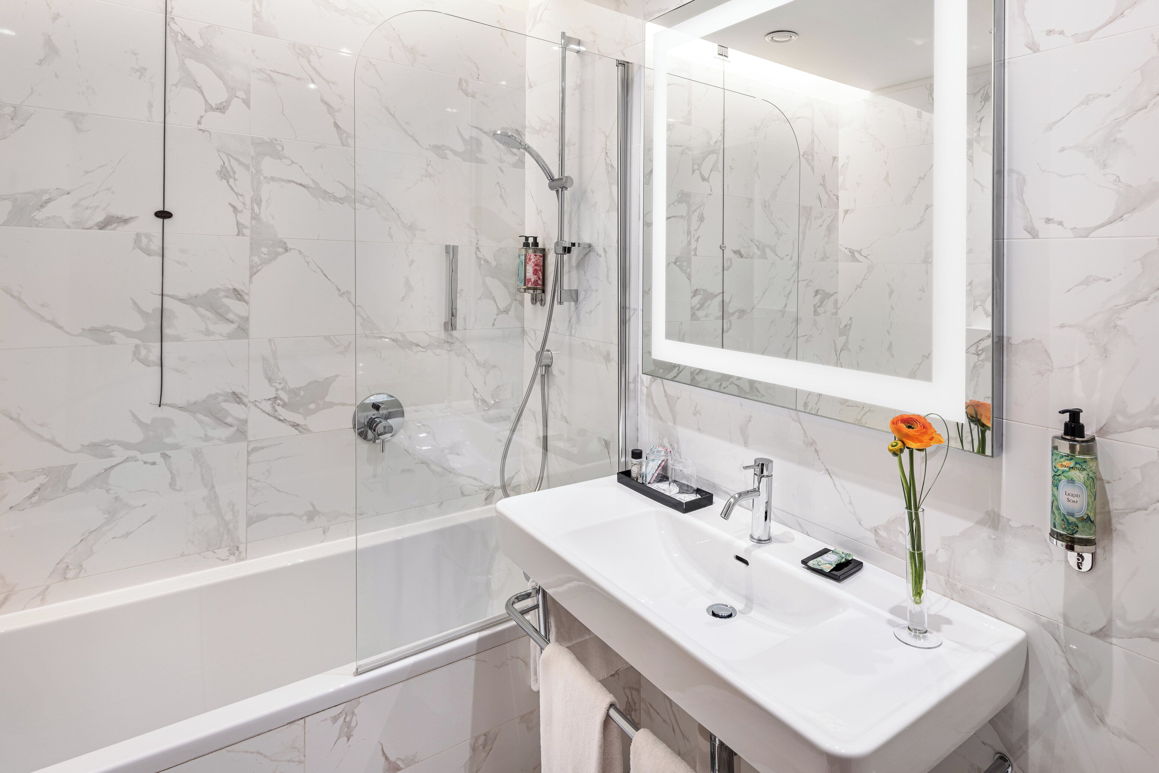 A modern bathroom with a glass-enclosed shower, a white sink, and a large mirror.