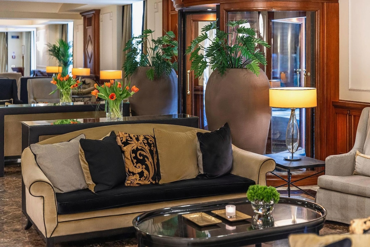 A hotel lobby with a sofa, a coffee table, and large decorative vases.