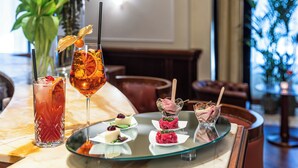 A bar area with a glass table displaying various drinks and appetizers. - Starhotels Majestic (Turin)