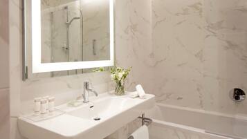 Un bagno con lavandino, specchio e doccia, tutto in bianco.