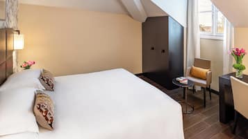 Une chambre d’hôtel avec un grand lit, une petite table avec une chaise, un bureau avec une chaise et une fenêtre avec des rideaux.