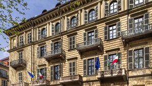 A historic building with multiple balconies, arched doorways, and flags. - Starhotels Majestic (Turin)