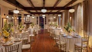 A formal dining room with multiple round tables, each set with white tablecloths, gold-rimmed plates, and gold chairs. - Hotel Provincial (New Orleans)