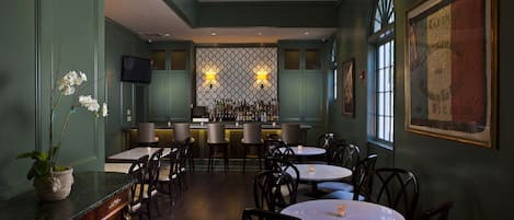 Un restaurante con zona de bar, varias mesas y sillas.