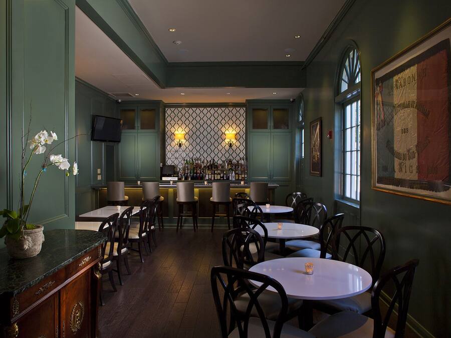 Un restaurante con zona de bar, varias mesas y sillas.