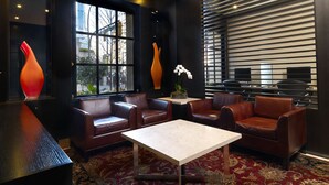 A modern lounge area with leather sofas, a marble coffee table, and a view of the city through large windows.