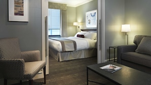 A hotel room with a bed, a sofa, a chair, a coffee table, and a framed picture on the wall.
