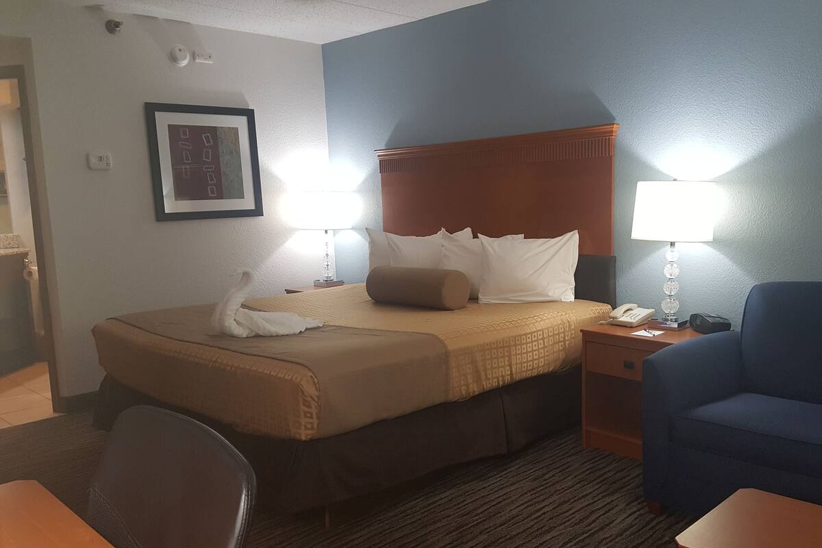 Quarto de hotel com cama, escrivaninha, cadeira e sofá azul.