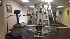 A gym with cardio equipment, weight machines, and a mirrored wall. - The Hotel@Dayton South (Dayton)